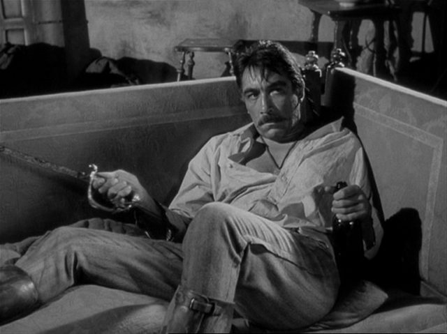 Anthony Quinn als Zapatas Bruder Eufemio, der mit Säbel und einer Flasche mit latent aggressivem Blick auf einem Sofa liegt.